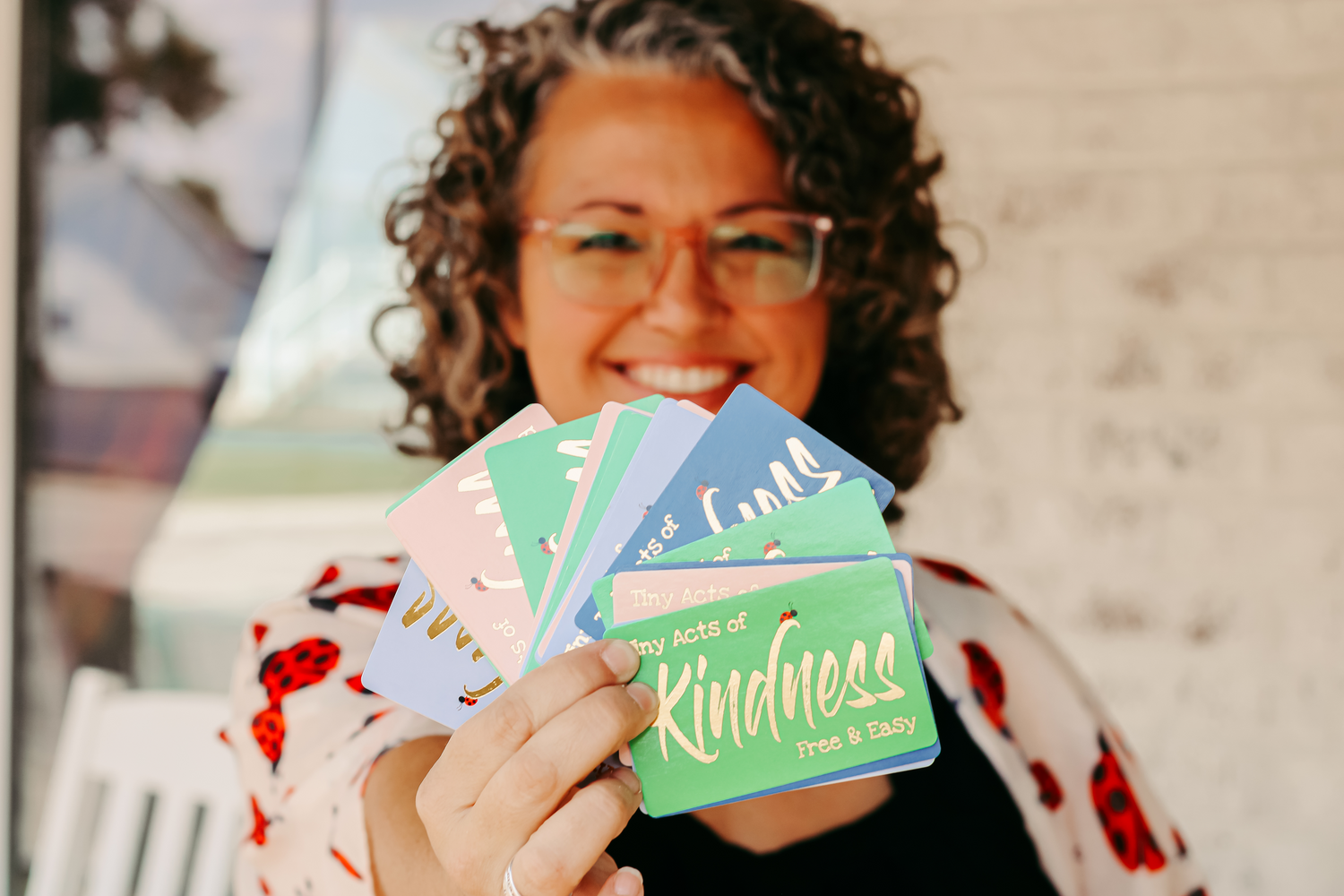 Gina Sachs, Creator of Kindness at tinyacts.co holding kindness cards